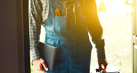 a plumber arriving for a maintenance job at a home with a toolbox and clipboard