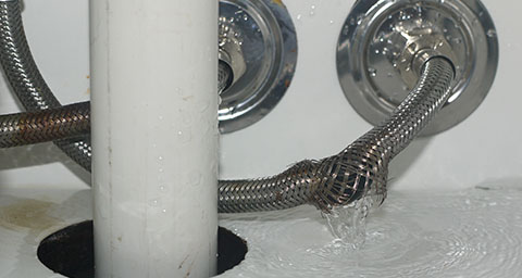 a burst water pipe leaking into the interior of a cupboard