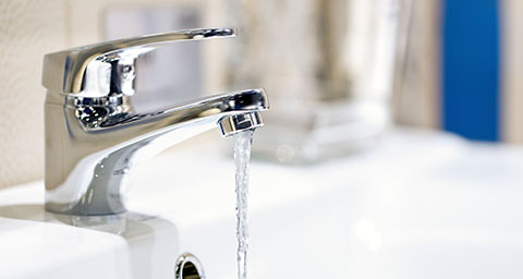 a tap on a bathroom sink with flowing water coming out of it