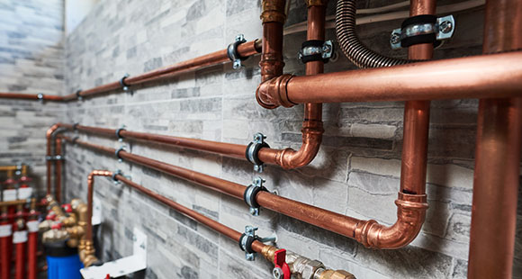 a set of copper water pipes fixed to a brick wall